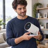 Person holding a compact smart mini projector in a contemporary living room setting.